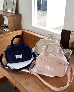 Close-up of corduroy bowling bags in navy, cream, and pink with adjustable straps