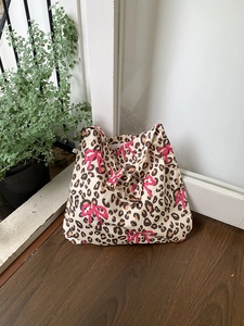 Detail of leopard print canvas tote bag featuring a decorative pink ribbon bow accent
