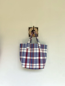 Detail of red white and blue plaid woven tote bag with durable handles and retro style