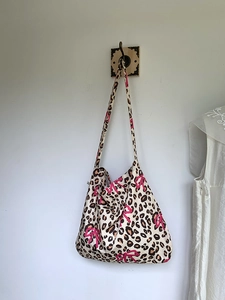 Detail of leopard print tote bag featuring a pink bow on a rustic wooden wall hook