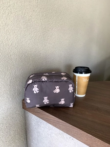Detail of dark brown cosmetic bag with cute bear patterns on a rustic wooden desk