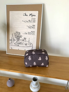 Close-up of a large capacity cosmetic bag with white bear pattern on wood shelf