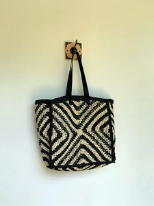 Detail of hand-woven striped tote bag showing geometric black and white knit texture