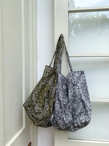 Detail of bohemian paisley canvas tote bags hanging on a white wooden door frame