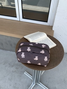 Detail of a large brown makeup bag featuring cute white bear prints and a zipper closure