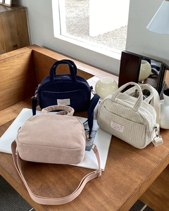 Detailed view of textured corduroy mini boston bags in navy, beige, and soft pink colors