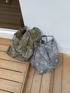 Top view of olive green and grey paisley canvas tote bags on outdoor wooden steps