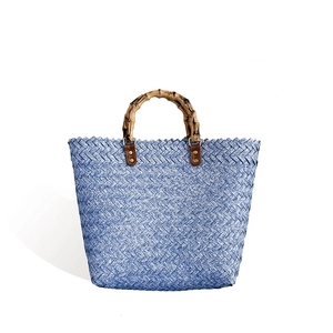 Blue woven tote bag with bamboo handles and vintage straw texture on white background