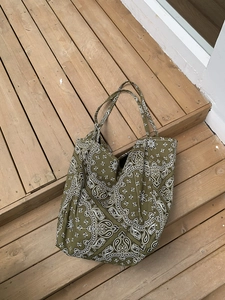Detailed close-up of army green canvas tote bag with white paisley pattern on wood floor