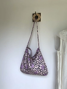 Detail of pink leopard print tote bag with star patterns hanging on a wooden hook
