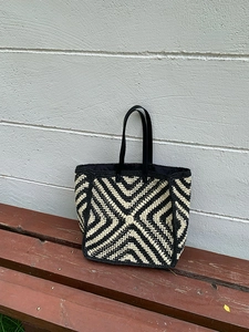 Close-up of bohemian crochet tote bag showing detailed black and beige geometric weaving