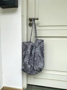 Detail of grey paisley canvas tote bag hanging on a wooden door handle for daily use