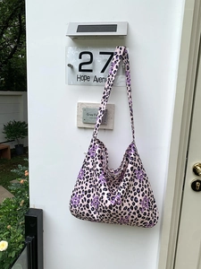 Detail of pink leopard print tote bag with purple star patterns on a white wall