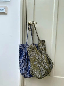 Detail of navy and olive paisley canvas tote bags hanging on a door handle