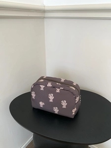 Quilted dark purple makeup bag with cute bear pattern on a black side table