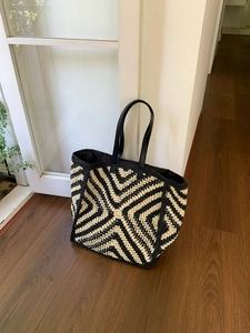 Detail of hand-woven striped tote bag with black leather shoulder strap and geometric pattern