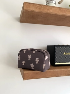 Close-up of lightweight nylon makeup bag with bear prints on a wooden shelf