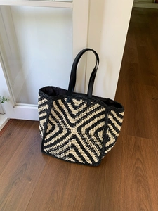 Close-up of a large crochet tote bag with black and white V-pattern and leather handles