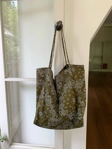 Detail of army green canvas tote bag with white paisley patterns hanging on a door