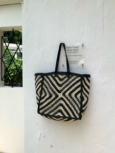 Detail of hand-woven tote bag with black and white geometric diamond patterns and long strap