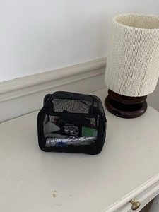 Detail view of black mesh toiletry bag showing nylon texture and top handle