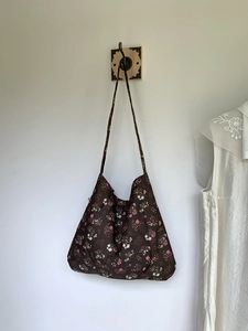 Brown floral canvas tote bag with pink flower patterns on a minimalist wooden hook