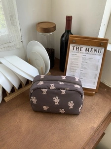 Detailed view of large cosmetic bag with cute bear pattern on a wooden table