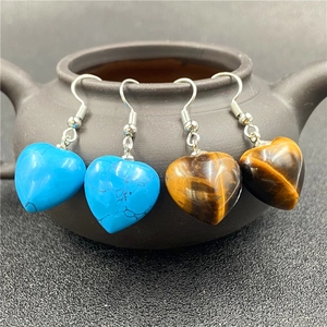 Detail of heart-shaped tiger eye and turquoise stone earrings hanging on a teapots rim