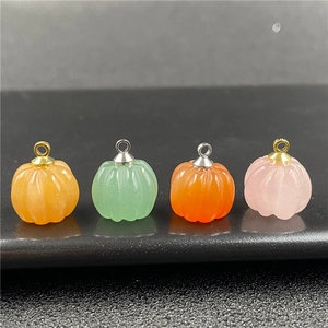 Vista macro di ciondoli in pietra colorata a forma di zucca con ganci in metallo dorato