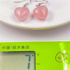 Natural heart-shaped rose quartz earrings with silver hooks shown on a digital scale