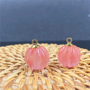 Vista macro di due ciondoli a zucca in quarzo rosa con anelli dorati su un tappeto