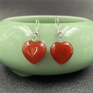 Detailed view of heart-shaped red agate stone earrings with polished silver hooks