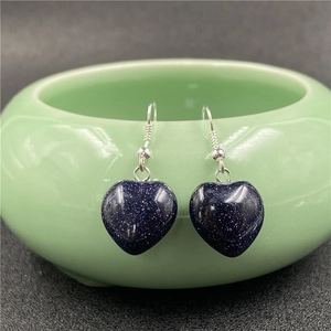 Detailed close-up of blue sandstone heart earrings hanging on a green ceramic bowl