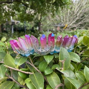 Détail d'une couronne de lune avec des cristaux de quartz aura violets et bleus sur des feuilles