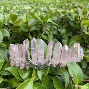 Détail de couronne en cristal rose avec pendentif lune sur feuilles vertes