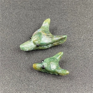 Detailed macro view of moss agate wolf head pendants with intricate stone carvings