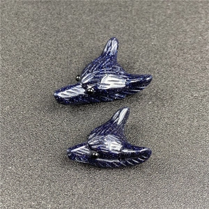 Detailed view of wolf head pendants carved from blue goldstone with metallic sparkles