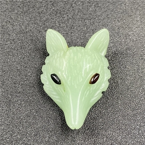 Macro detail of hand-carved light green fox head pendant with fine engraved textures