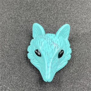 Macro shot of hand-carved turquoise fox pendant with detailed textures and black bead eyes