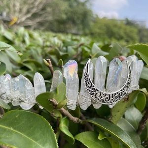 Détail d'une couronne de lune en quartz aura bohème avec fil d'argent sur feuilles vertes