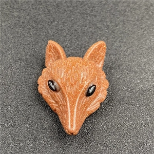Detailed view of fox head pendant carved from sparkling brown goldstone with black eyes