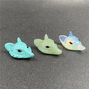 Detailed macro shot of hand-carved fox pendants in turquoise, jade, and opal