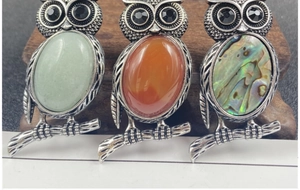 Detailed close-up of vintage owl brooches with gemstone inlay and metallic feathers