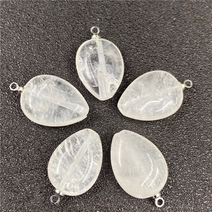 Close-up of five teardrop crystal pendants with silver loops on black surface