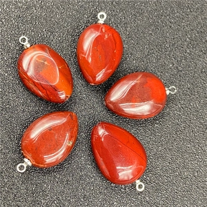 Detailed view of five red teardrop crystal pendants with silver loops on dark background