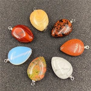 Teardrop pendants in assorted natural stones with silver bails arranged on black surface