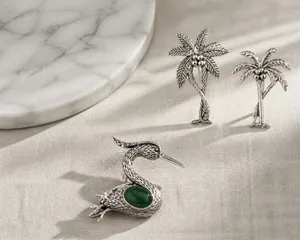 Macro view of vintage silver bird brooch featuring detailed green gemstone inlay