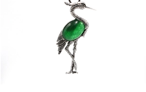 Detailed relief carving of an antique silver crane pin with an oval green gemstone