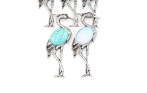 Detailed close-up of crane brooches with turquoise and opal-like gemstone inlay