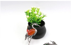 Close-up of red gemstone inlaid crane brooch with detailed silver metal wing texture